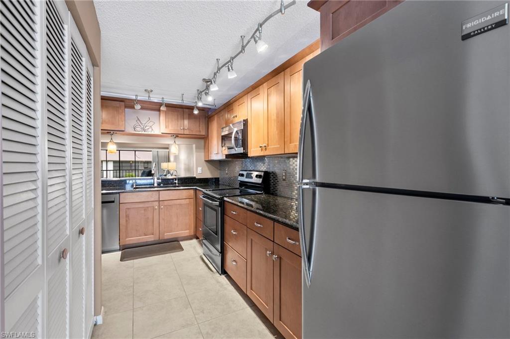 236 Pebble Beach Circle, Unit A202 Naples, FL 34113 - Photo 10 of 25 a kitchen with stainless steel appliances granite countertop a refrigerator a sink a stove and white cabinets