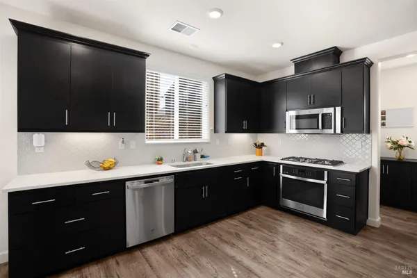 a kitchen with stainless steel appliances granite countertop a stove a sink and a microwave