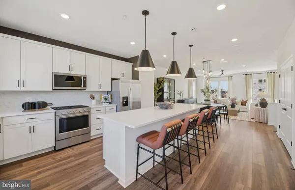 a kitchen with stainless steel appliances kitchen island granite countertop a stove top oven a sink a dining table and chairs with wooden floor