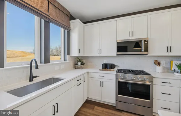 a kitchen with stainless steel appliances granite countertop white cabinets a sink and a oven