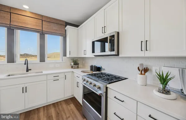 a kitchen with stainless steel appliances white cabinets and a stove top oven
