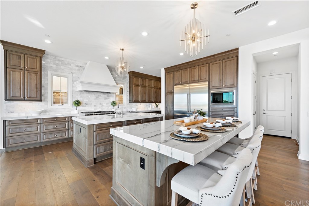 186 Leafy Pass Irvine, CA 92602 - Photo 19 of 59 a kitchen with a stove a sink dishwasher a dining table and chairs with wooden floor