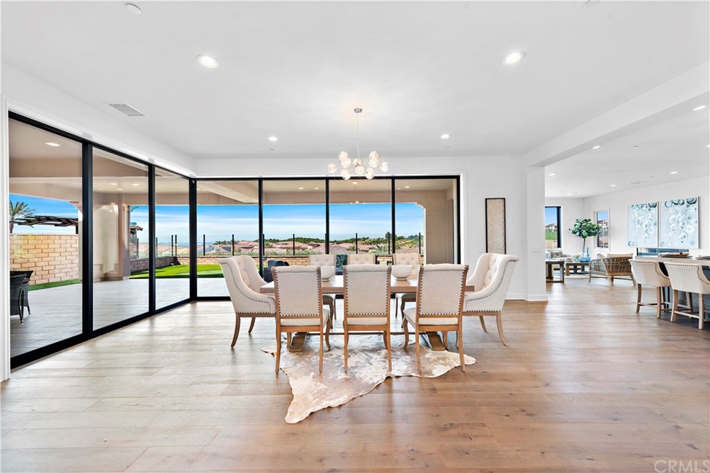 186 Leafy Pass Irvine, CA 92602 - Photo 8 of 59 a dining room with furniture a chandelier and wooden floor