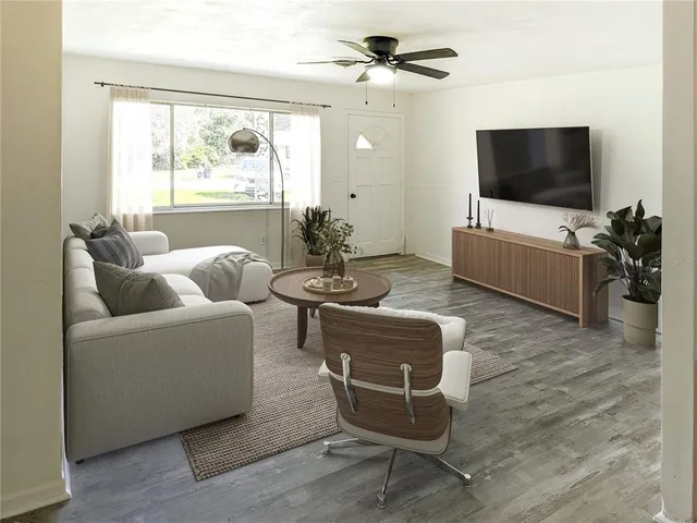 a living room with furniture a flat screen tv and a floor to ceiling window