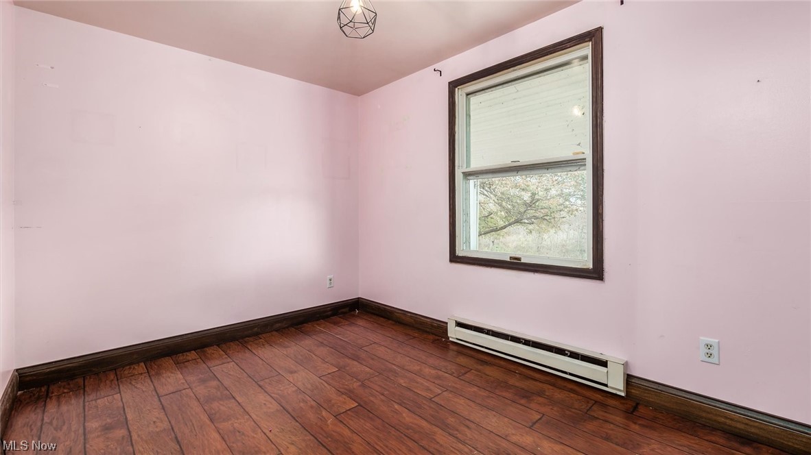 1730 Mollies Rock Road Dresden, OH 43821 - Photo 13 of 24 Empty room with dark hardwood / wood-style flooring and a baseboard heating unit