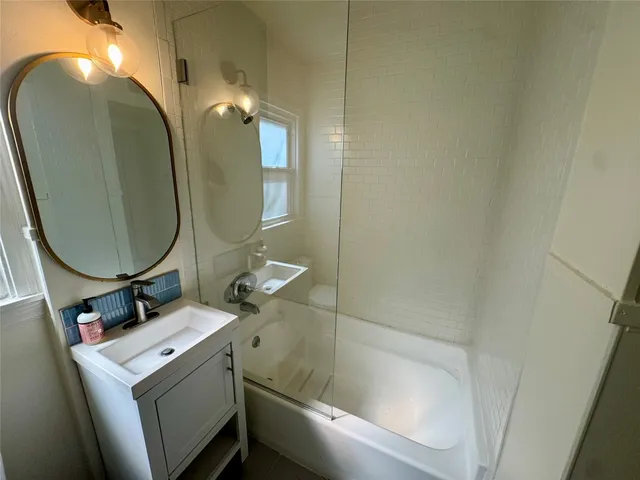 a bathroom with a sink and mirror with bathtub