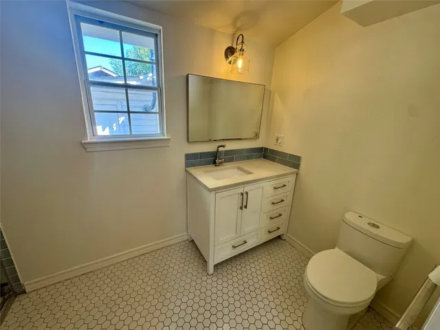 a bathroom with a granite countertop toilet sink and mirror