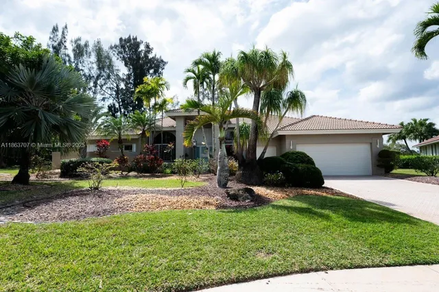 a view of a house with a yard and palm trees