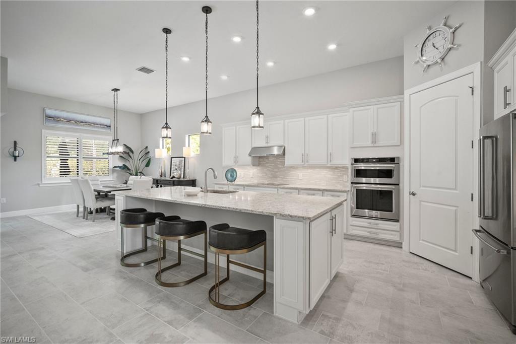 14227 Wild Timber Court Estero, FL 33928 - Photo 21 of 49 a kitchen with kitchen island a dining table chairs sink and cabinets