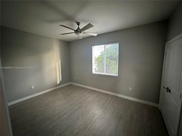 an empty room with wooden floor fan and windows