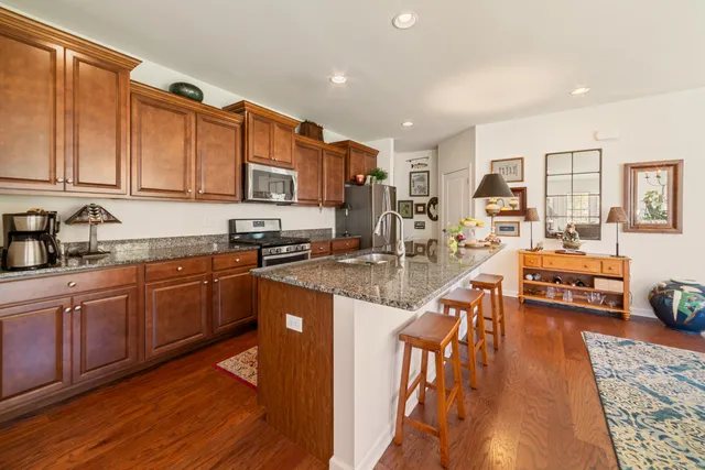 a kitchen with stainless steel appliances granite countertop a sink stove and wooden cabinets with wooden floor