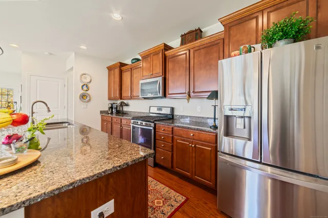 a kitchen with stainless steel appliances granite countertop a refrigerator a stove and a sink