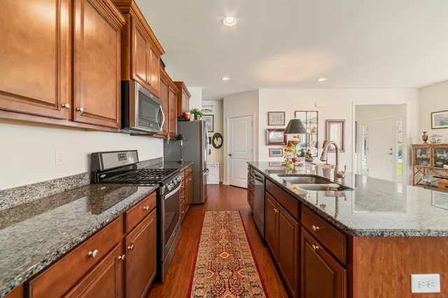 a kitchen with stainless steel appliances granite countertop a sink a stove and a wooden cabinets