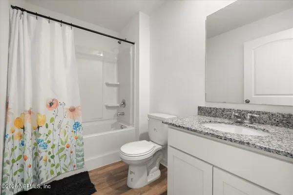 a bathroom with a granite countertop sink a toilet and shower