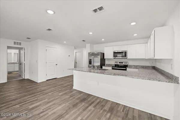 a large white kitchen with kitchen island a sink a stove a refrigerator and white cabinets
