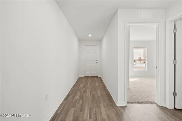 a view of a hallway with wooden floor and a bathroom