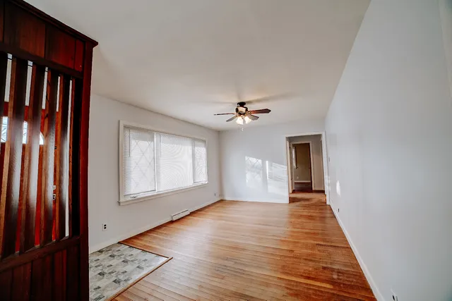 a view of an empty room with wooden floor and a window