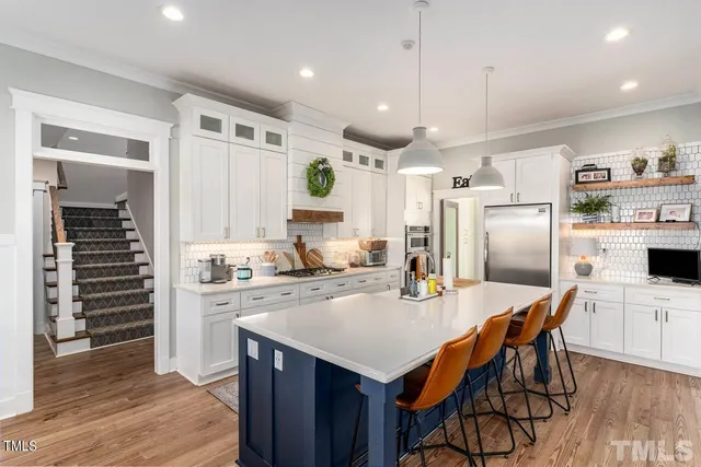 a kitchen with stainless steel appliances kitchen island granite countertop a table chairs and a refrigerator