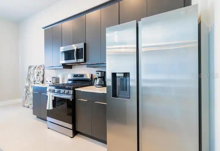 7740 Sandy Ridge Drive, Unit 223 Kissimmee, FL 34747 - Photo 11 of 52 a kitchen with stainless steel appliances granite countertop a refrigerator a stove a sink and a microwave