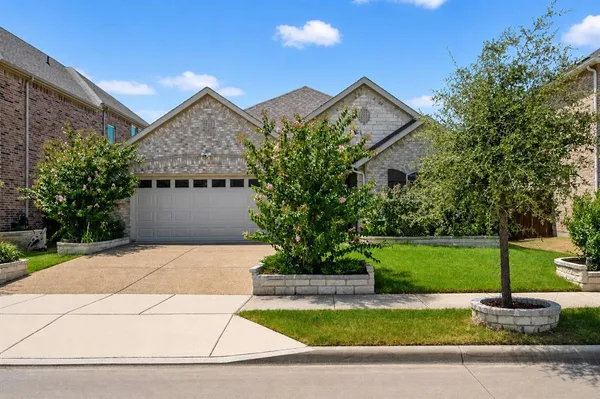 a front view of a house with a garden and trees