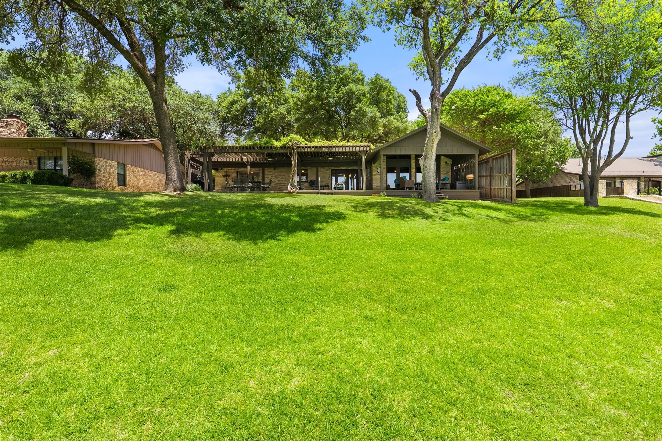 141 Perry Lane Kingsland, TX 78639 - Photo 7 of 40 A spacious lawn unfolds before a dwelling featuring a broad deck under a charming pergola.