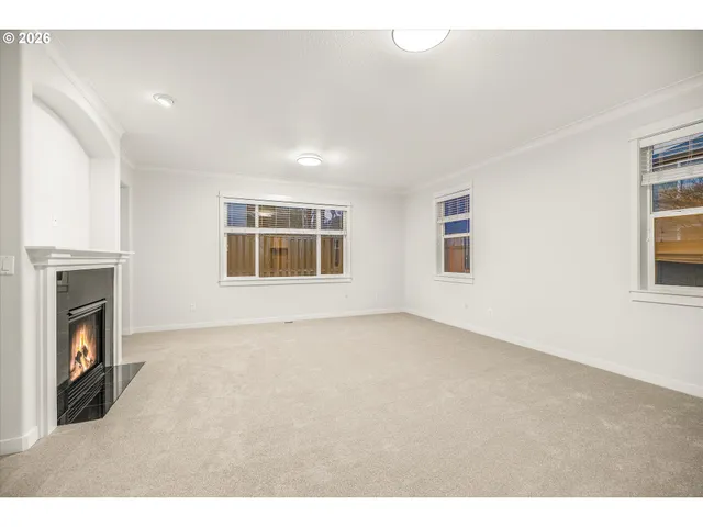 a view of an empty room with a window and fireplace