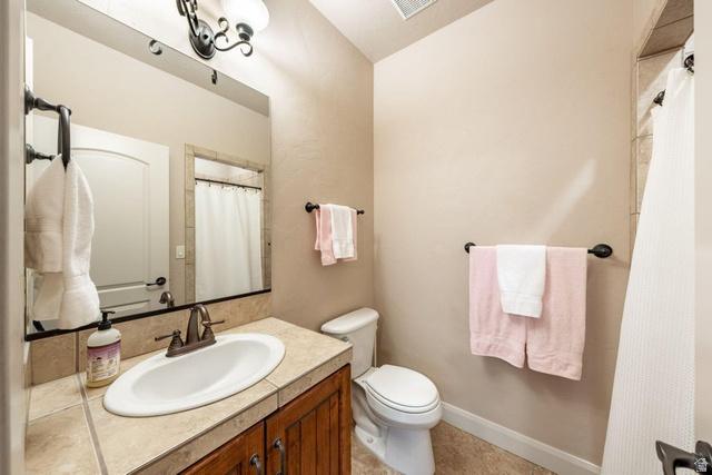 1609 East 10 S Street St. George, UT 84790 - Photo 44 of 68 Bathroom vanity featuring a tiled countertop, undermount sink, and wood-finish cabinetry