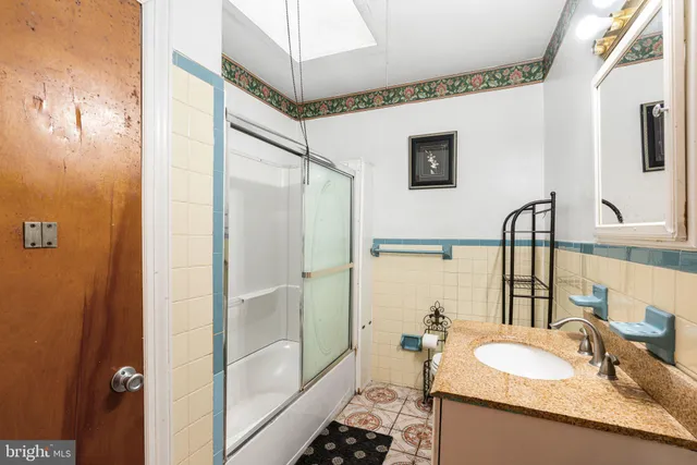 a bathroom with a granite countertop sink a mirror and shower