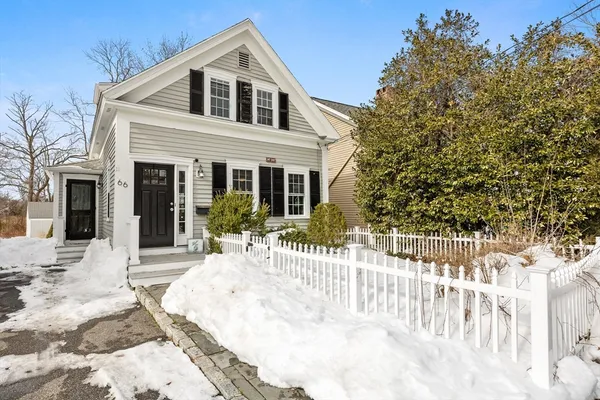 a view of white house with a small yard and wooden fence