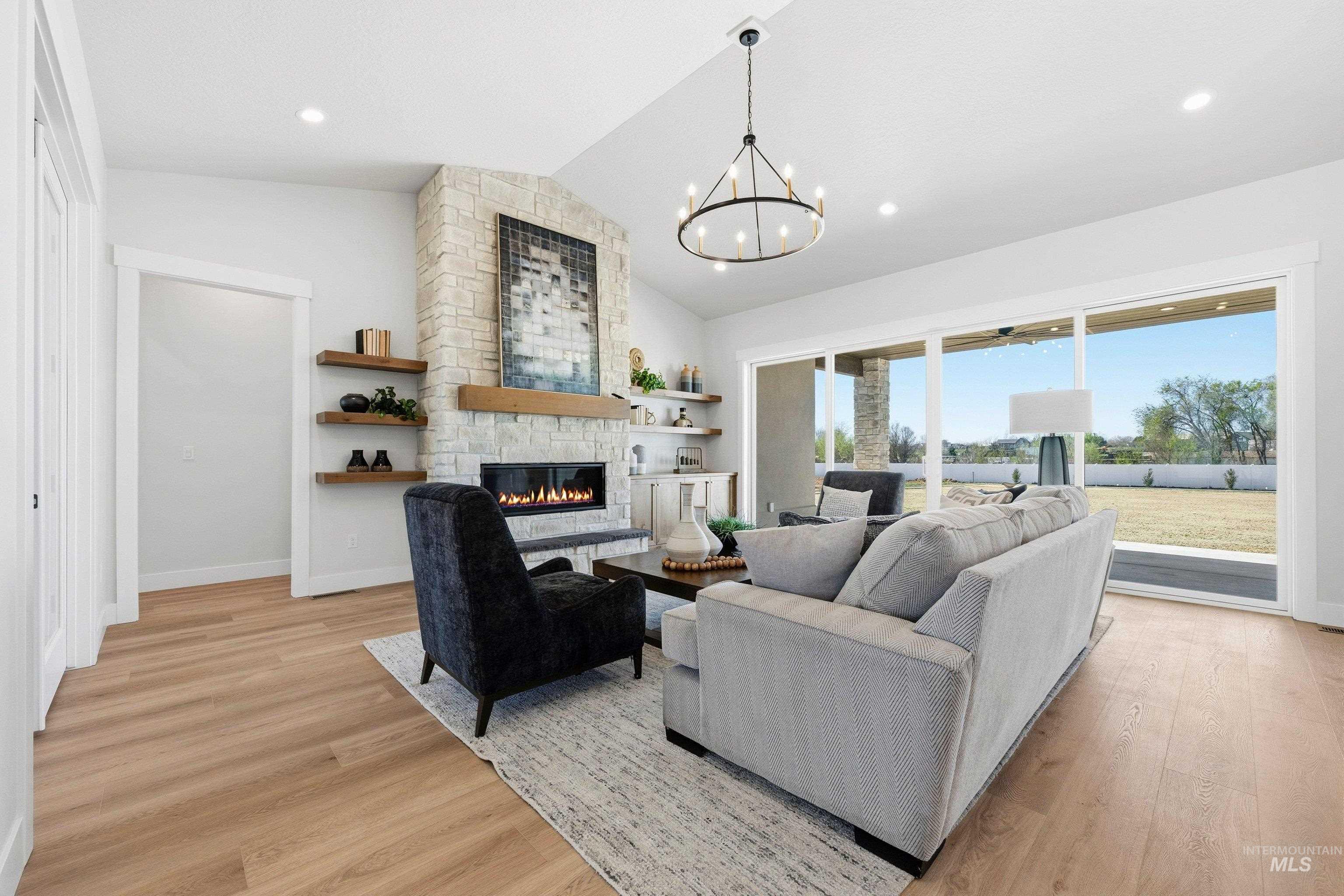 24897 Ardmore Court Caldwell, ID 83607 - Photo 22 of 47 Living room with light wood finished floors, a chandelier, and a fireplace