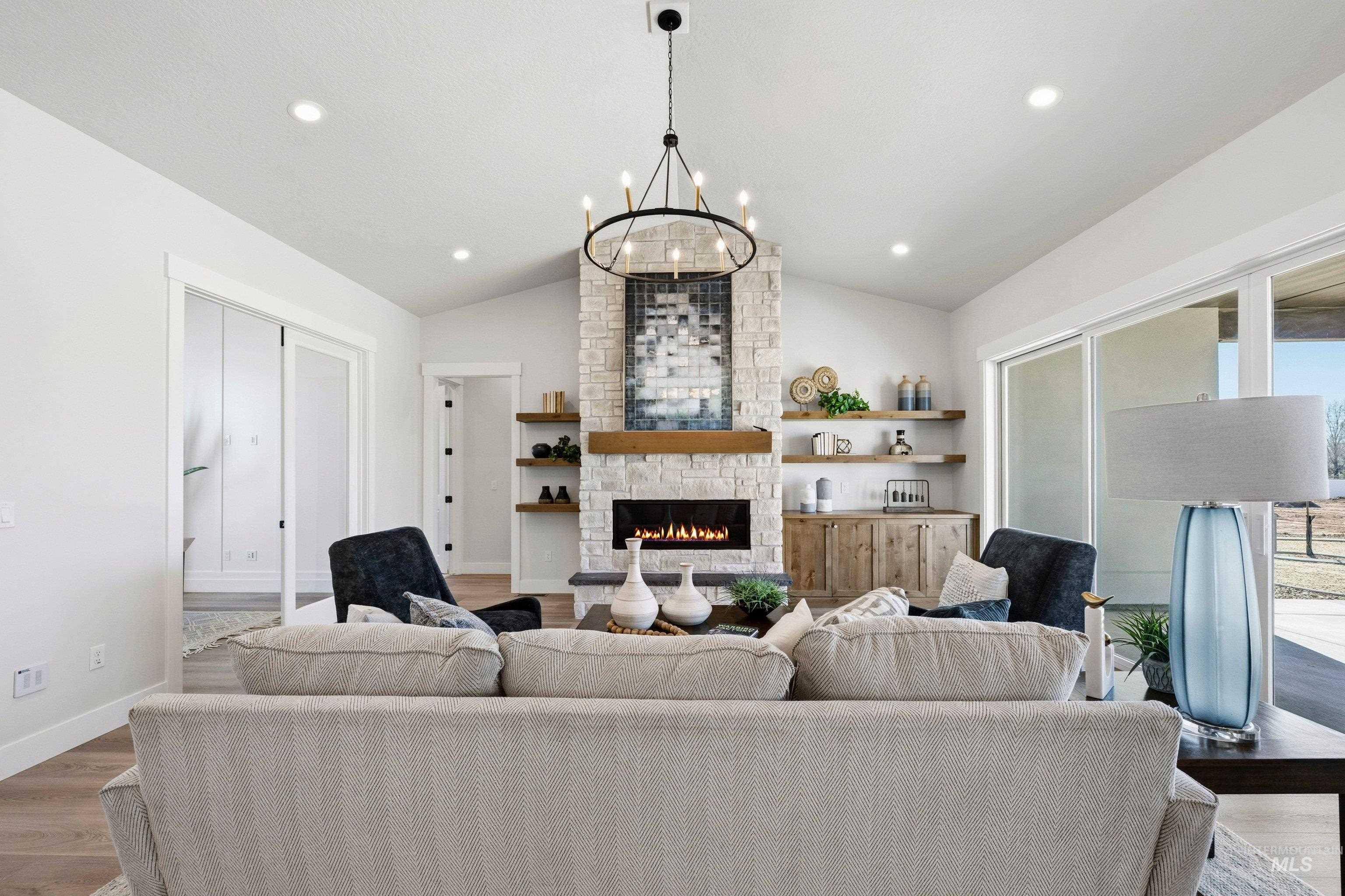 24897 Ardmore Court Caldwell, ID 83607 - Photo 25 of 47 Living room with wood finished floors, a chandelier, lofted ceiling, and a fireplace