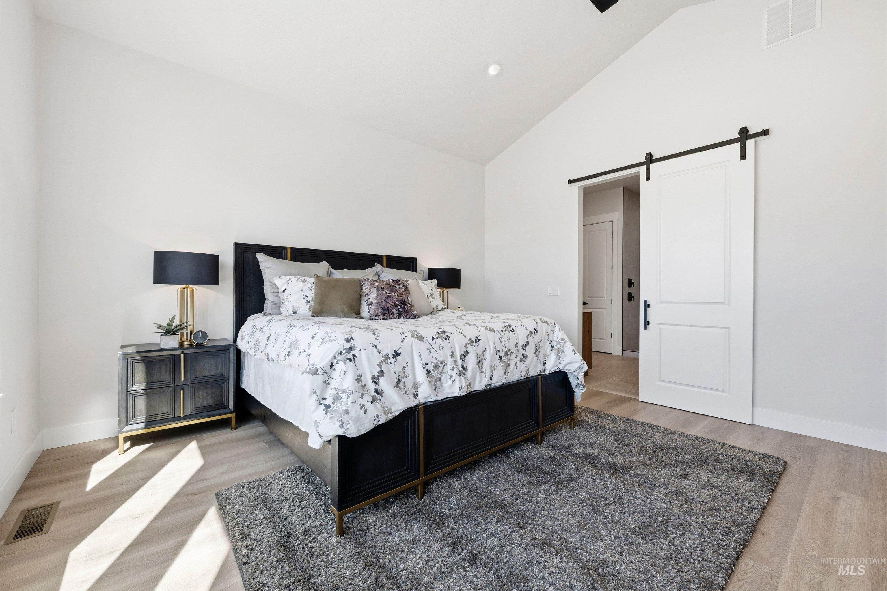 24897 Ardmore Court Caldwell, ID 83607 - Photo 37 of 47 Bedroom featuring a barn door, vaulted ceiling, light wood finished floors, recessed lighting, and a ceiling fan