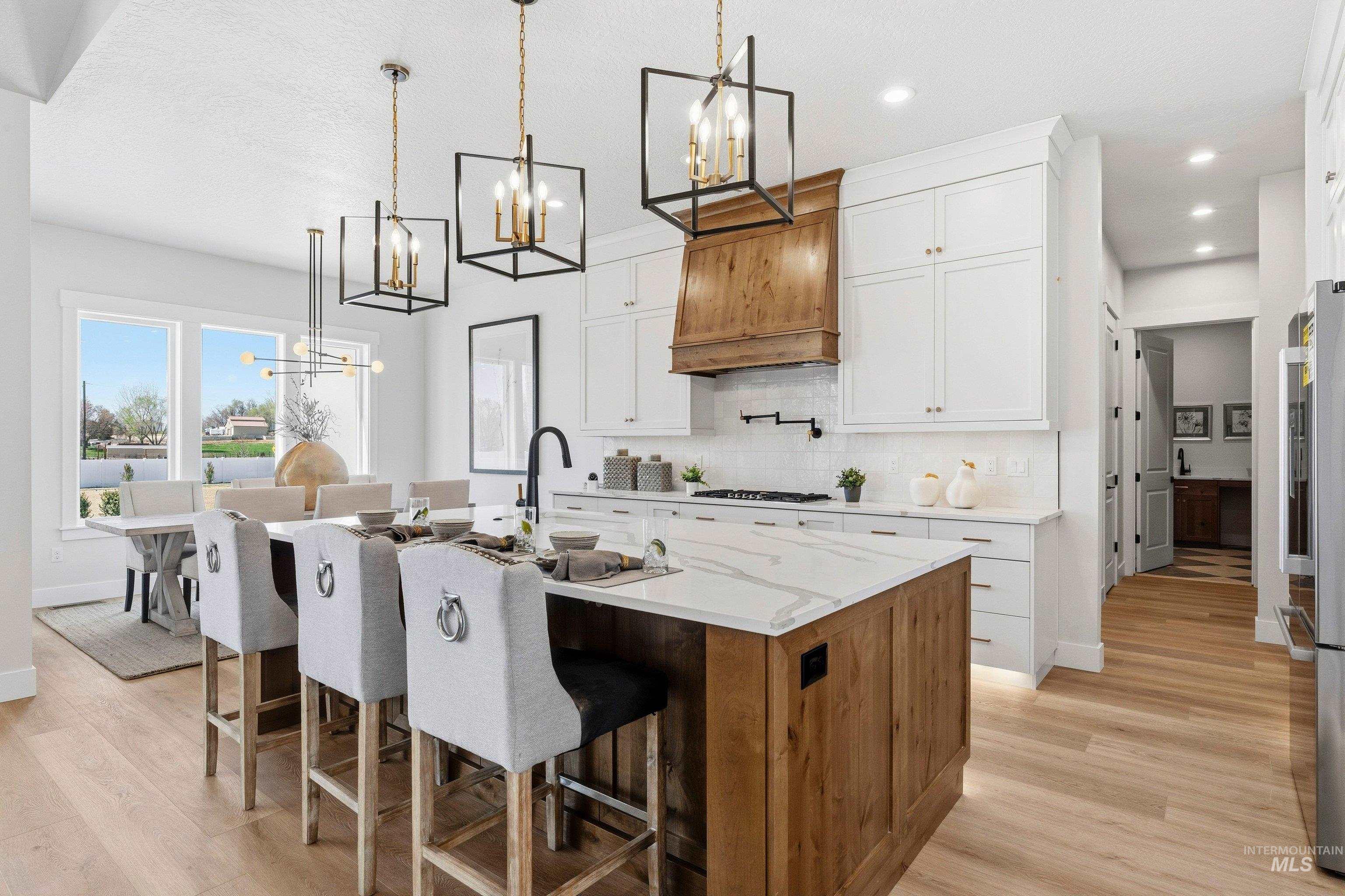 24897 Ardmore Court Caldwell, ID 83607 - Photo 9 of 47 Kitchen with a chandelier, a kitchen bar, two tone color scheme, light stone countertops, and a center island with sink