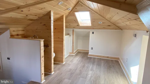 a view of a hallway with wooden floor and a bathroom