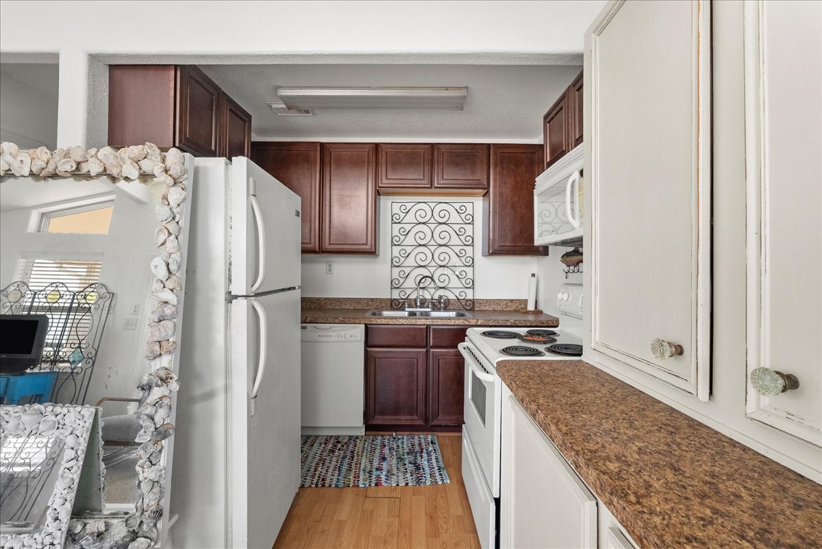 819 Seashell Drive Surfside Beach, TX 77541 - Photo 22 of 36 Cozy kitchen with a warm, inviting feel. It features wooden cabinetry, a white refrigerator, and an electric stove. The countertops have a granite-like appearance, and a decorative backsplash adds charm. A seashell-framed mirror adds a unique touch.