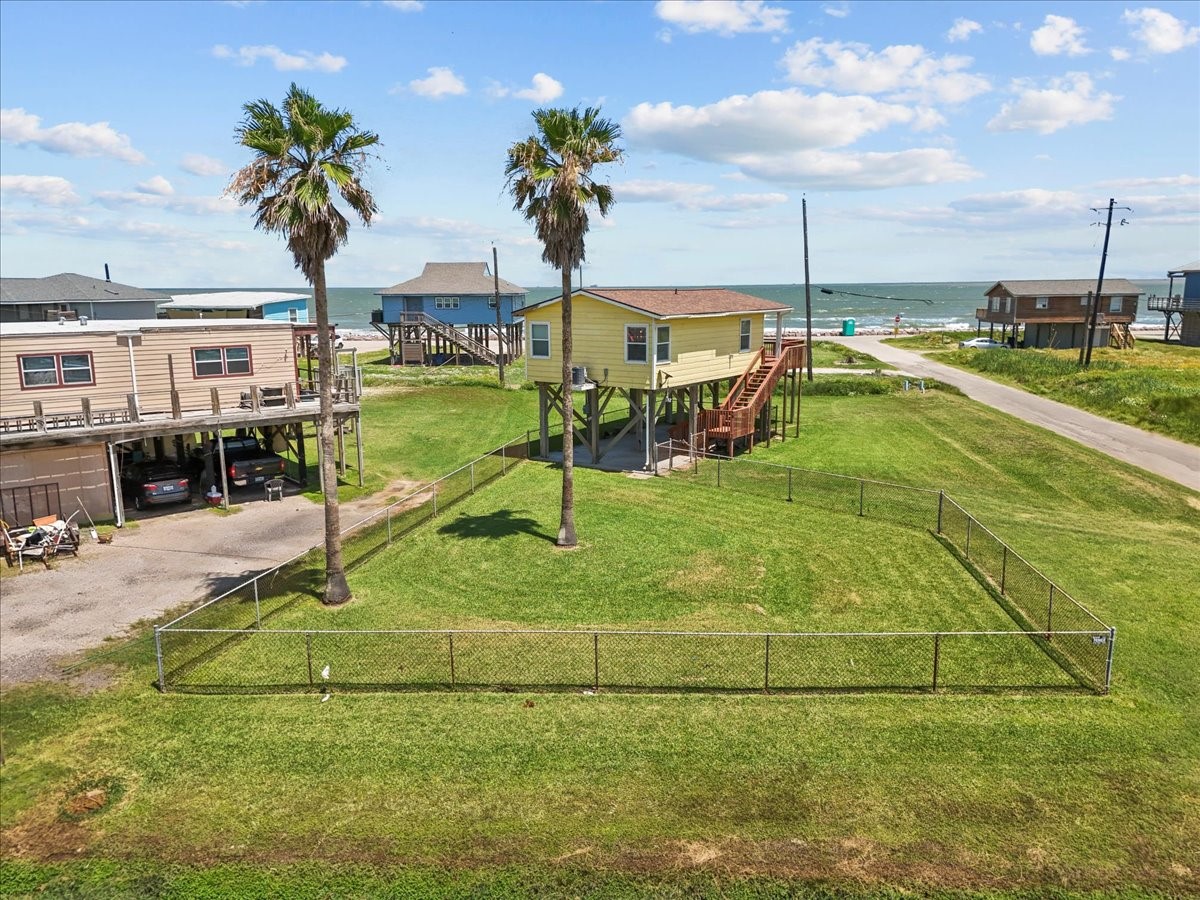819 Seashell Drive Surfside Beach, TX 77541 - Photo 30 of 36 This coastal property features a charming elevated yellow house with a spacious fenced yard. It's located near the water, offering scenic ocean views and easy beach access, perfect for seaside living.