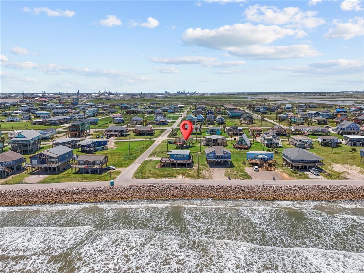 819 Seashell Drive Surfside Beach, TX 77541 - Photo 33 of 36 This photo showcases a coastal neighborhood with charming homes, each on spacious lots. The property in question is highlighted, positioned near the shoreline, offering stunning ocean views and easy beach access, ideal for those seeking a serene seaside lifestyle.
