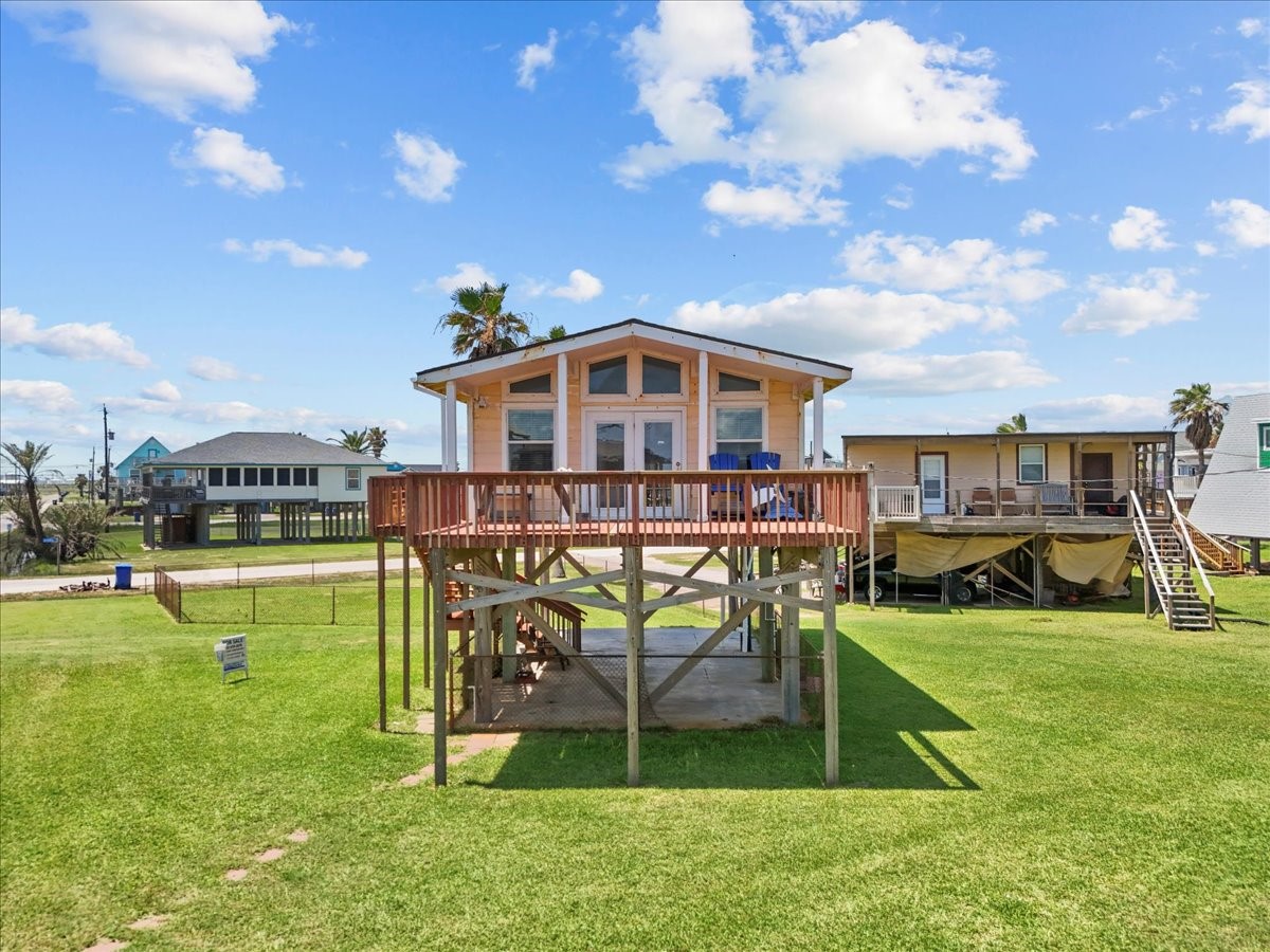 819 Seashell Drive Surfside Beach, TX 77541 - Photo 9 of 36 This elevated beach house features a spacious wooden deck, large windows, and sits on a grassy lot with nearby homes. It's perfect for enjoying coastal views and outdoor living.