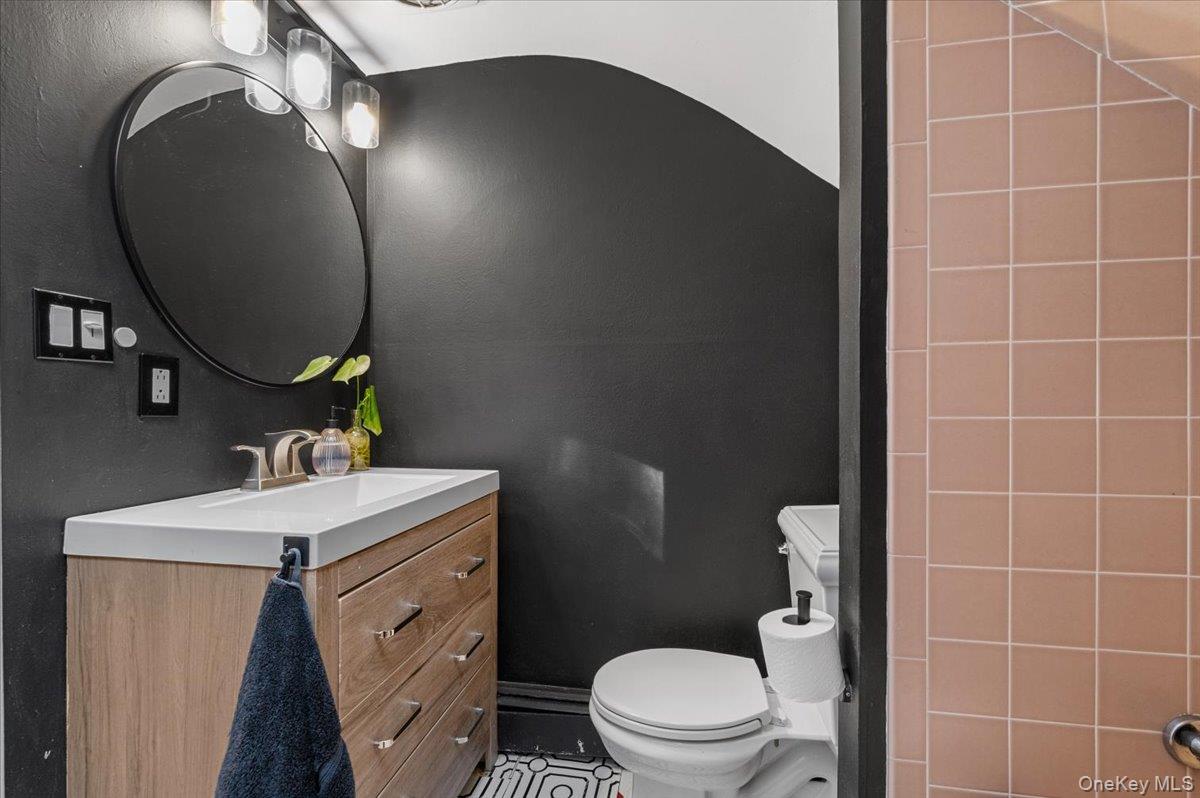 10 Rancher Place Huntington, NY 11743 - Photo 29 of 44 Modern bathroom featuring a wood-finish vanity with an integrated sink, brushed nickel faucet, and a circular mirror