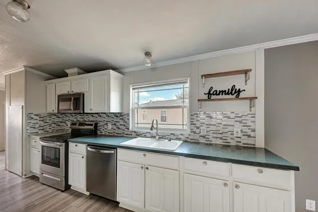 a kitchen with stainless steel appliances kitchen island granite countertop a stove and a sink