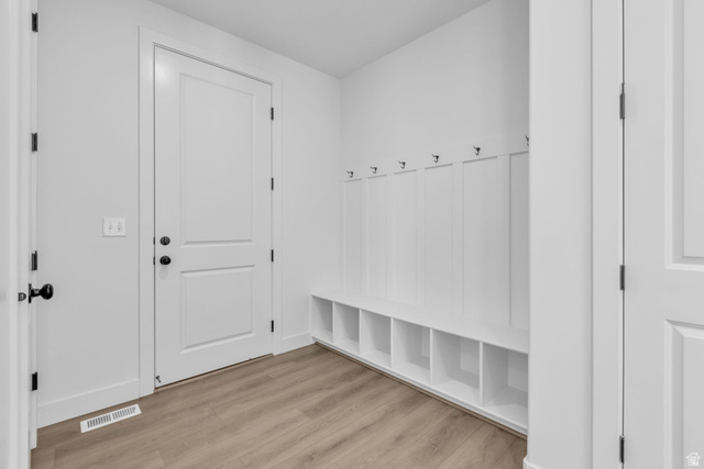 2923 Scarlet Road, Unit 145 Eagle Mountain, UT 84005 - Photo 10 of 18 Entryway from garage featuring a built-in cubbies and bench, white wall paneling, and multiple coat hooks.