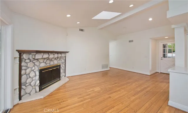 a view of empty room with wooden floor and fireplace