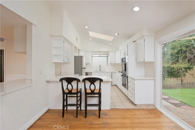 a kitchen with stainless steel appliances a table chairs refrigerator and wooden floor