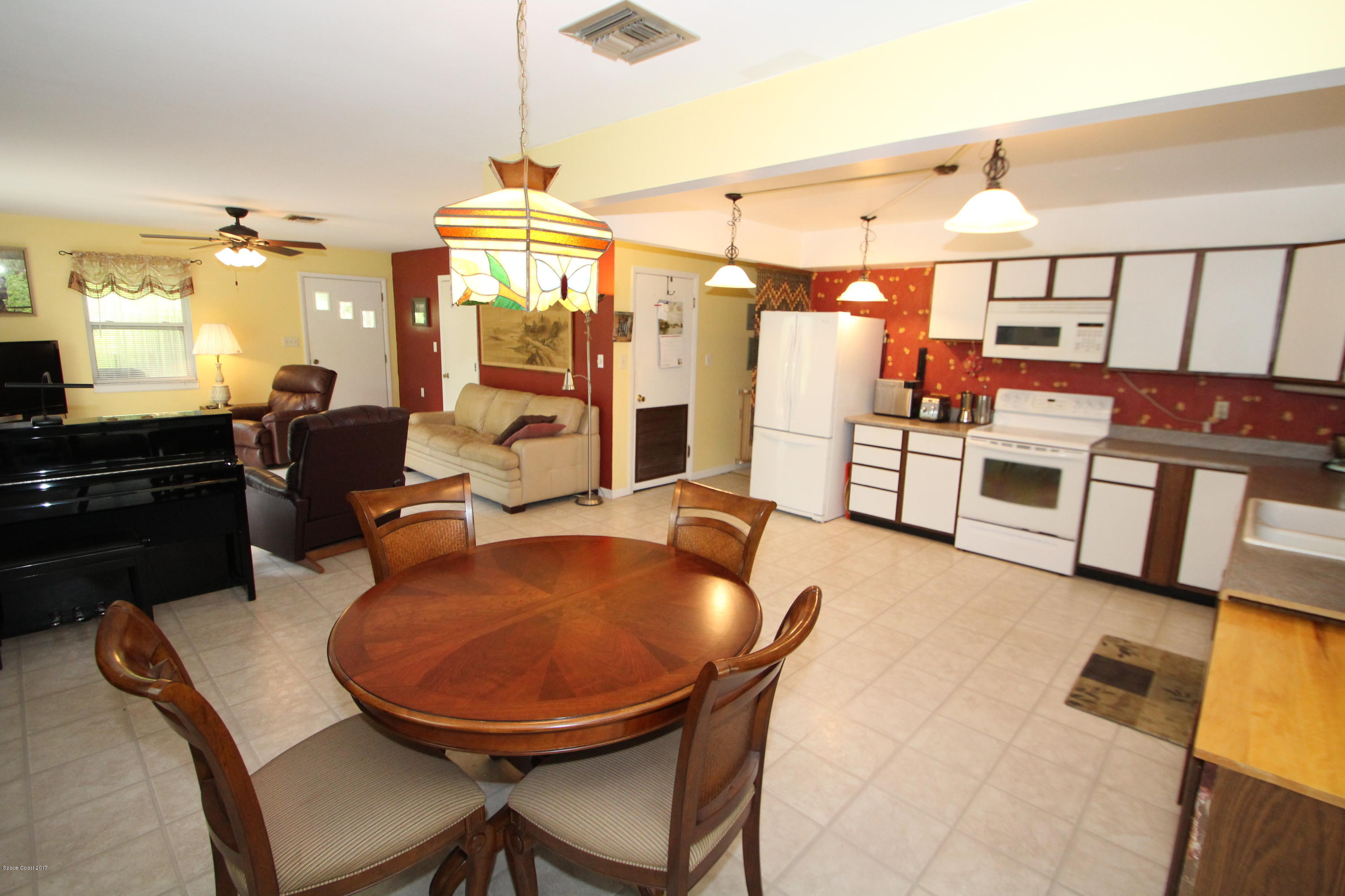1666 Emmaus Road Northwest Palm Bay, FL 32907 - Photo 3 of 15 a kitchen with stainless steel appliances granite countertop a stove a sink a refrigerator a dining table and chairs with wooden floor