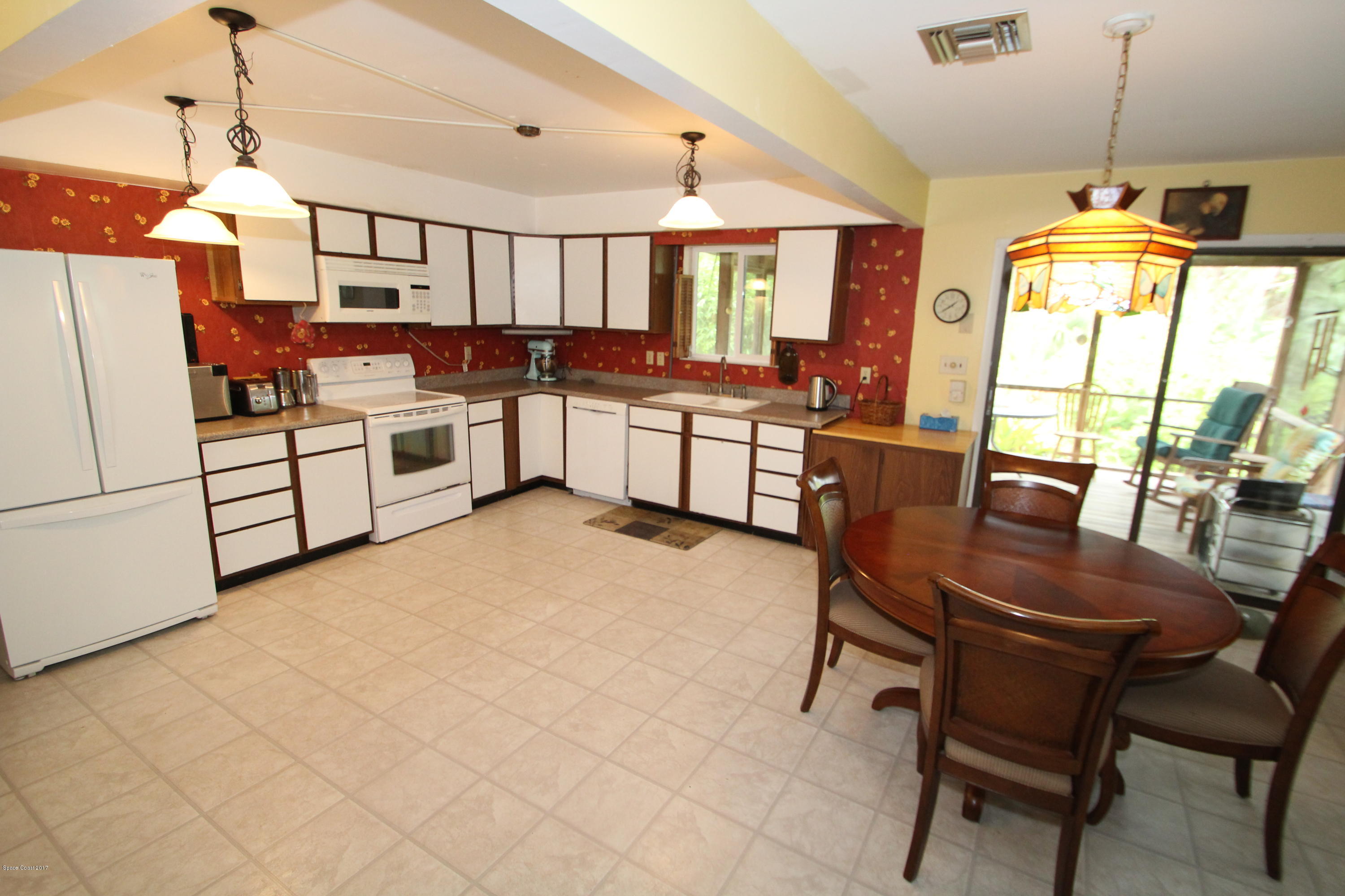 1666 Emmaus Road Northwest Palm Bay, FL 32907 - Photo 4 of 15 a kitchen with stainless steel appliances kitchen island granite countertop a stove a sink a dining table and chairs with wooden floor