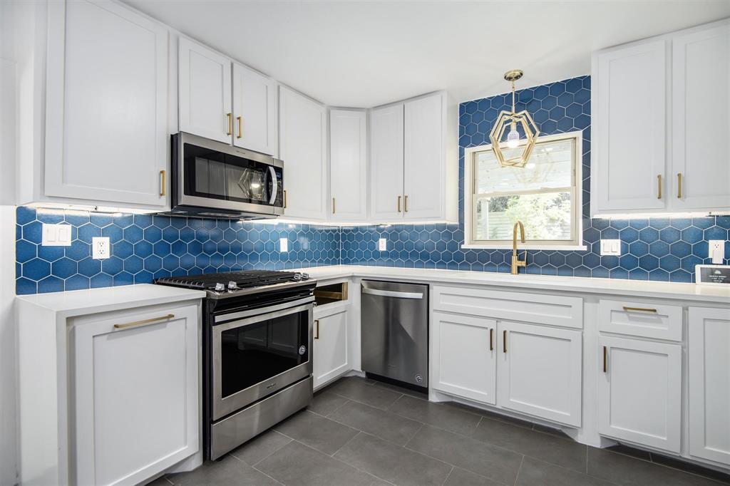 a kitchen with granite countertop white cabinets stainless steel appliances and a sink