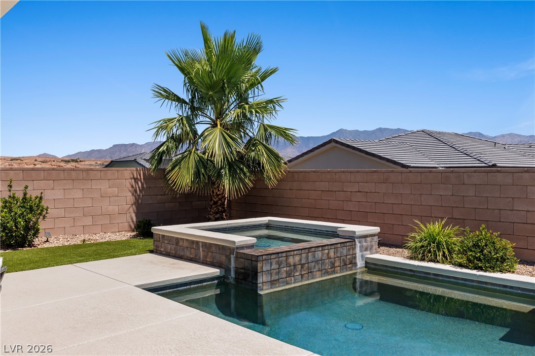 1436 Manassas Ridge Mesquite, NV 89027 - Photo 61 of 77 A desert oasis with a sparkling pool and spa, set against a backdrop of rolling mountains.