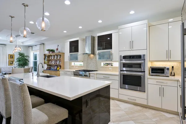 a kitchen with a refrigerator a stove a sink a dining table and chairs