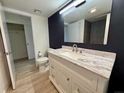 a bathroom with a granite countertop sink a toilet and a mirror