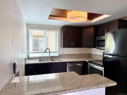 a kitchen with stainless steel appliances granite countertop a sink and a refrigerator